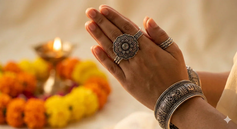 Indian women hands in Anjali mudra with blurred background is a creamy bokeh of a flickering brass diya and vibrant orange marigold garlands  