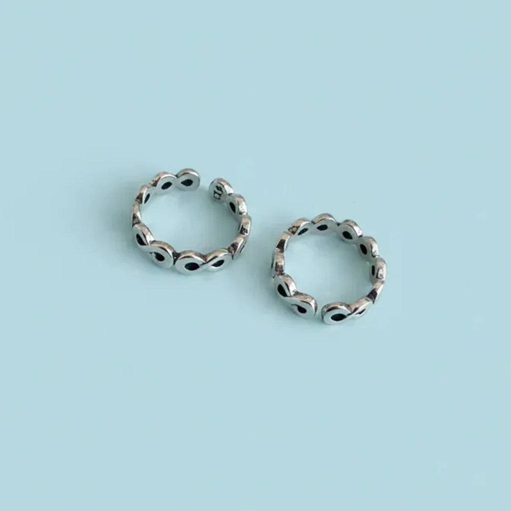 Flat lay image of Infinity Link Oxidized Toe Rings on solid background