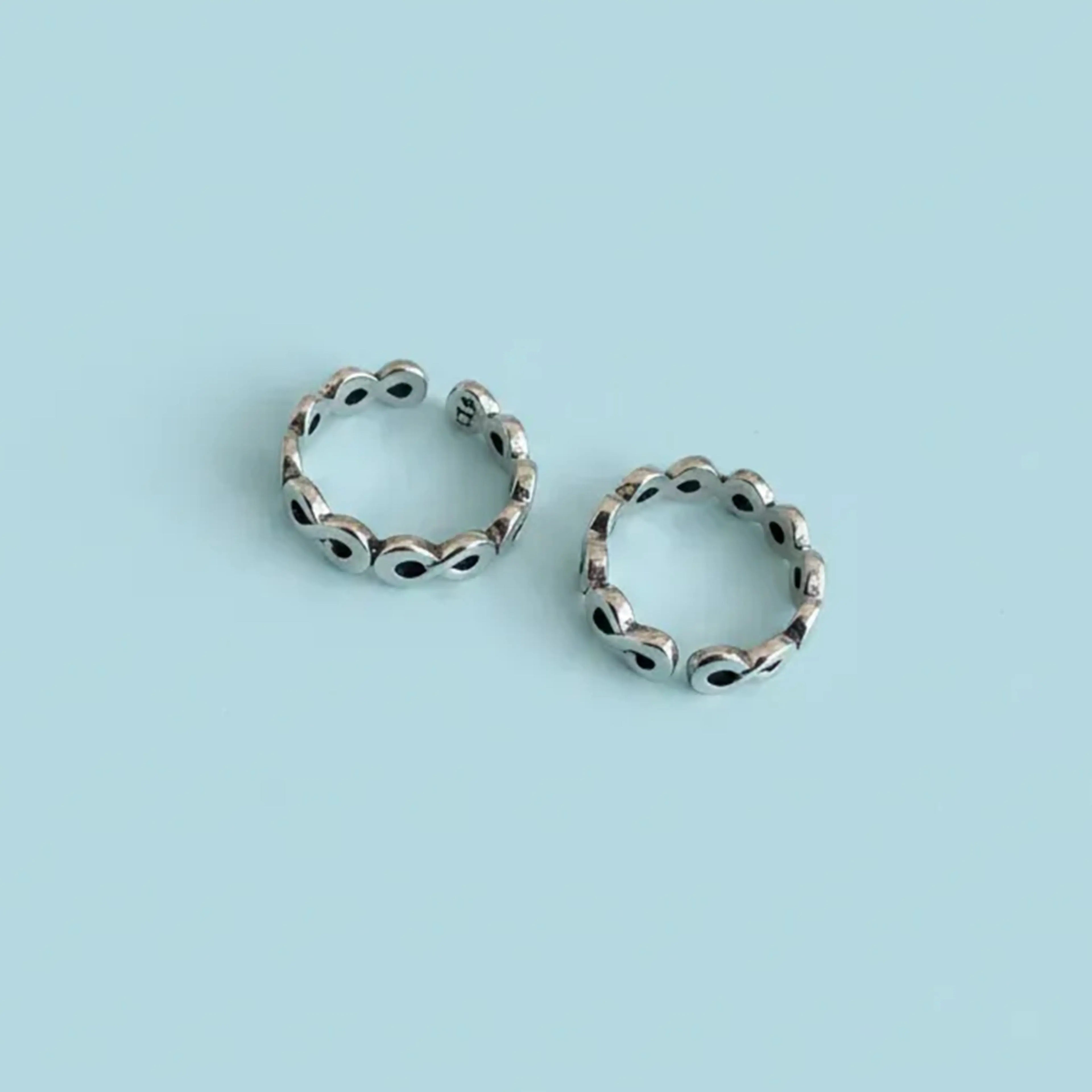 Flat lay image of Infinity Link Oxidized Toe Rings on solid background