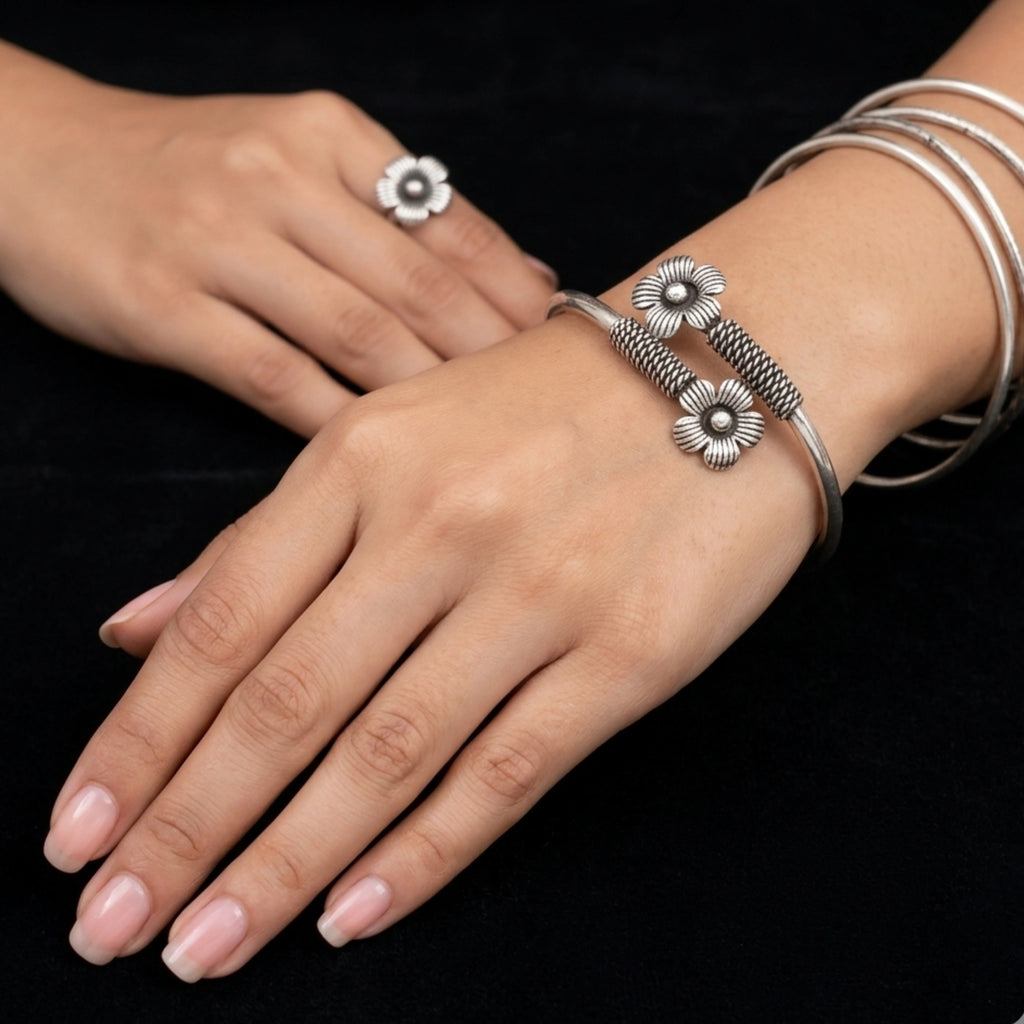 Silver bracelet with floral design on a wrist against a black background