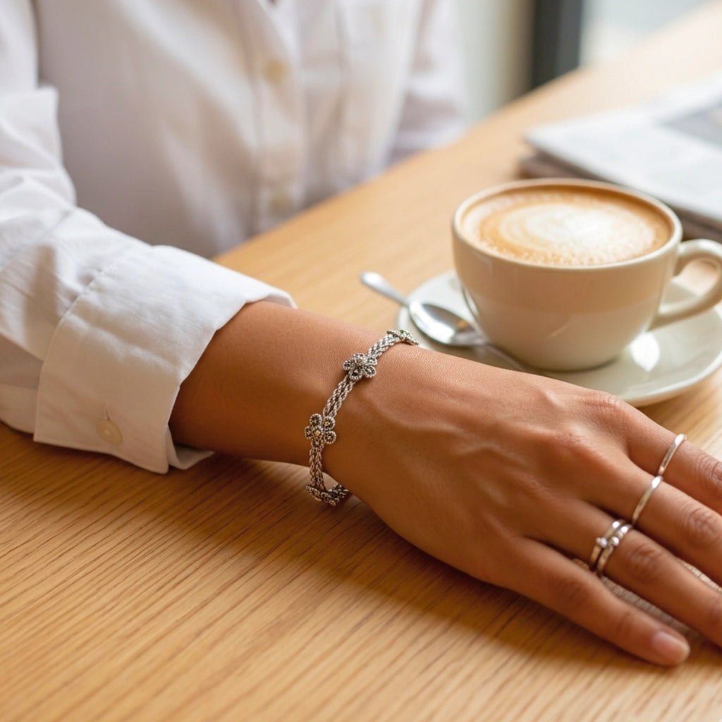 Hand with bracelet and ring on a wooden table with a cup of coffee