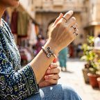 Person wearing multiple rings and a bracelet on a blurred street background