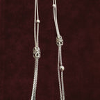 Closeup of Double-Strand Filigree Orbit Anklet Pair on a maroon background
