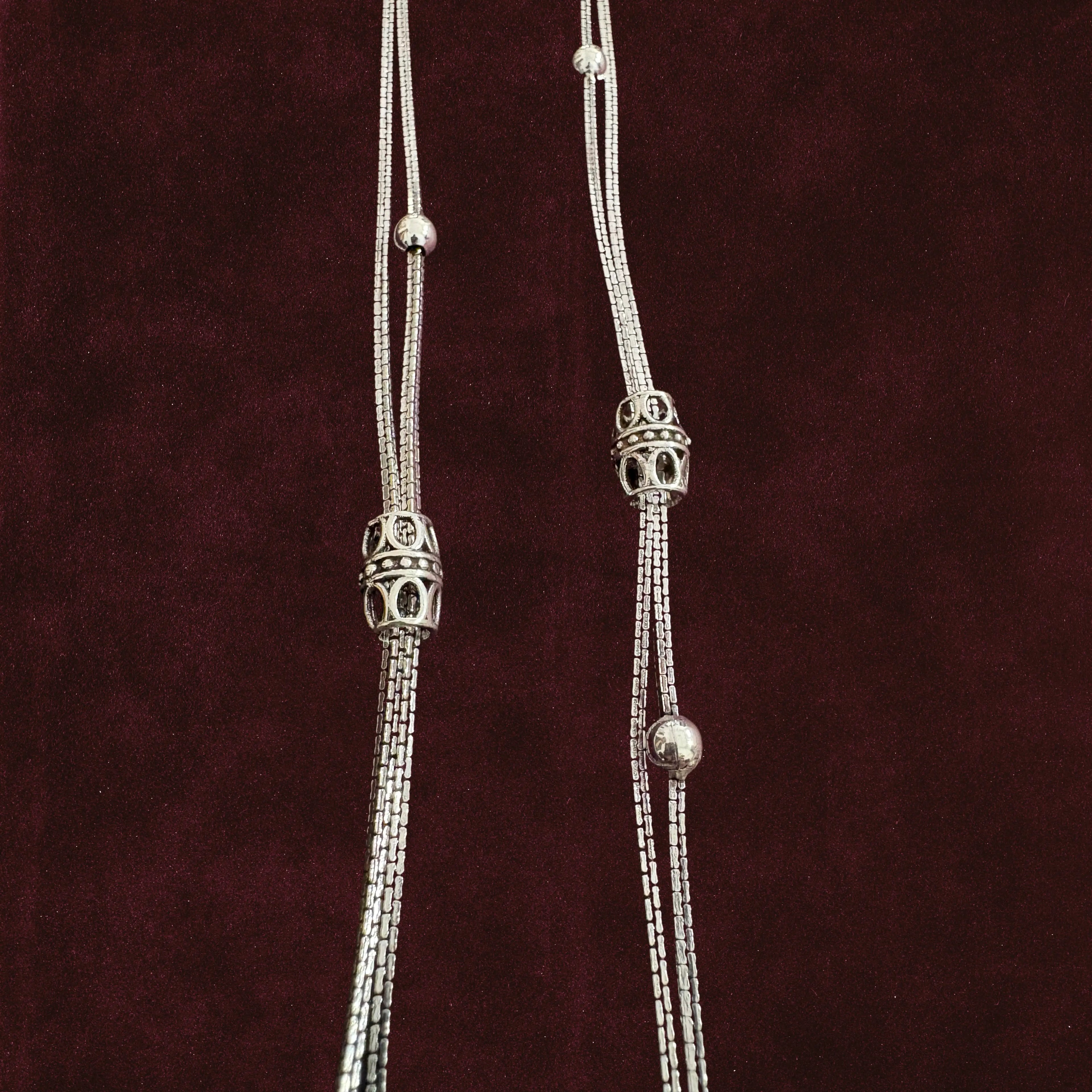 Closeup of Double-Strand Filigree Orbit Anklet Pair on a maroon background