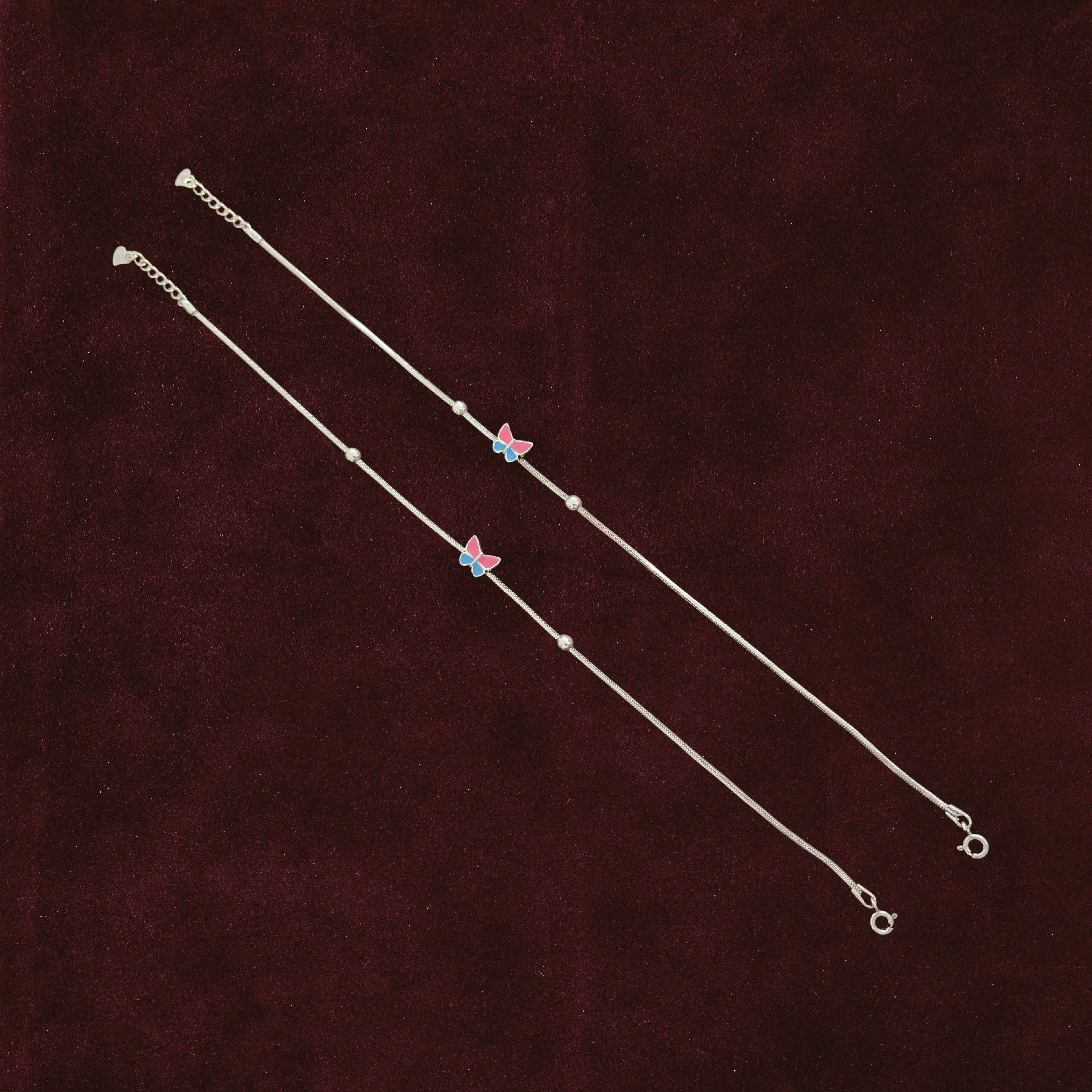 Fluttering Dual-Tone Butterfly Anklet Pair on a maroon background