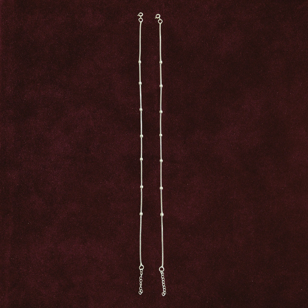 Silver dew drop anklet pair on maroon background