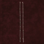 Silver dew drop anklet pair on maroon background