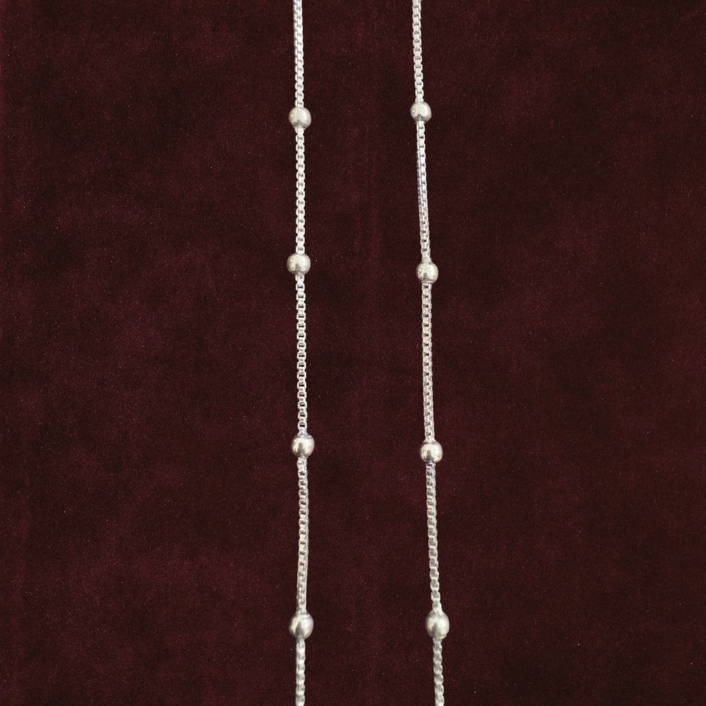 Silver dew drop anklet pair closeup on solid background