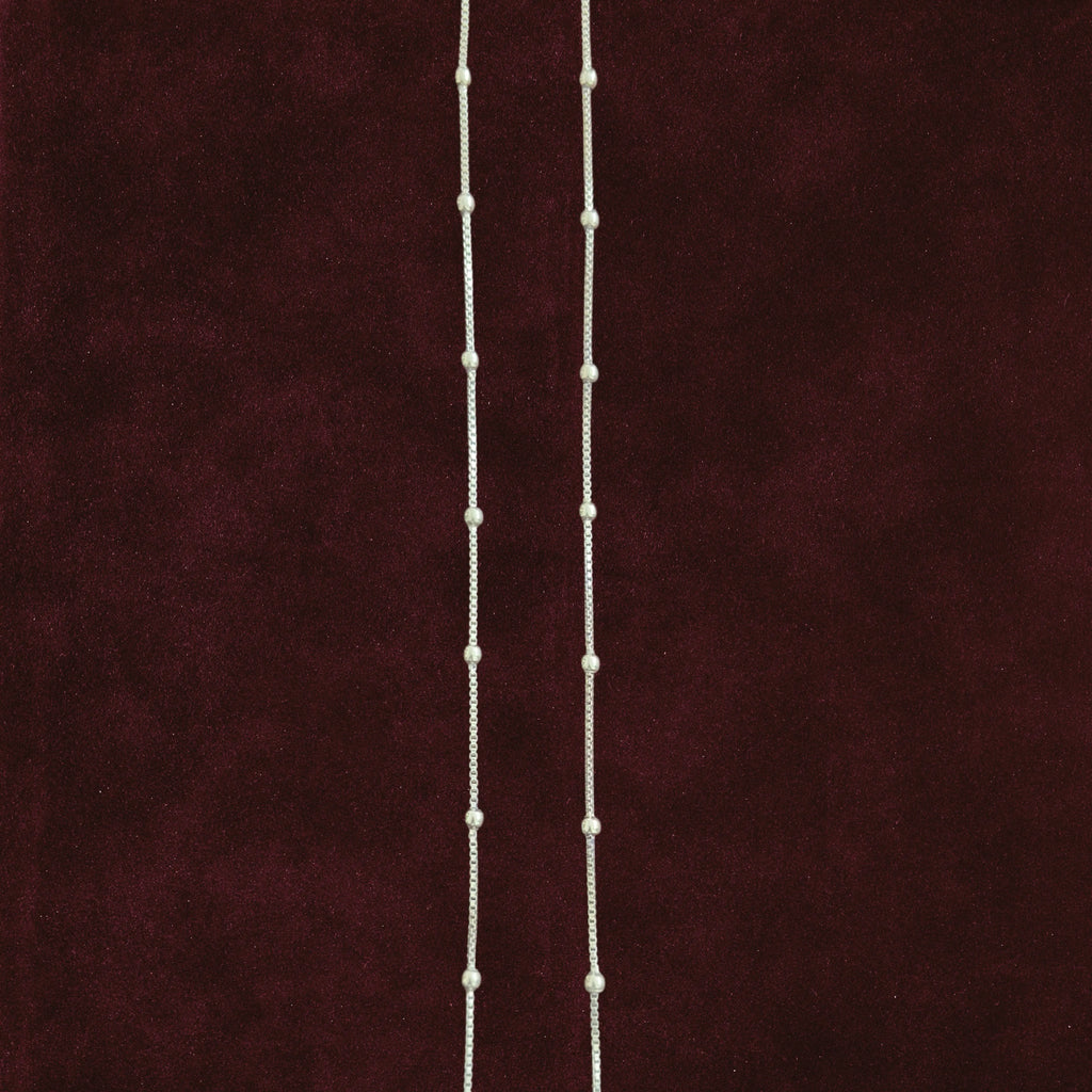 Silver dew drop anklet pair on maroon background