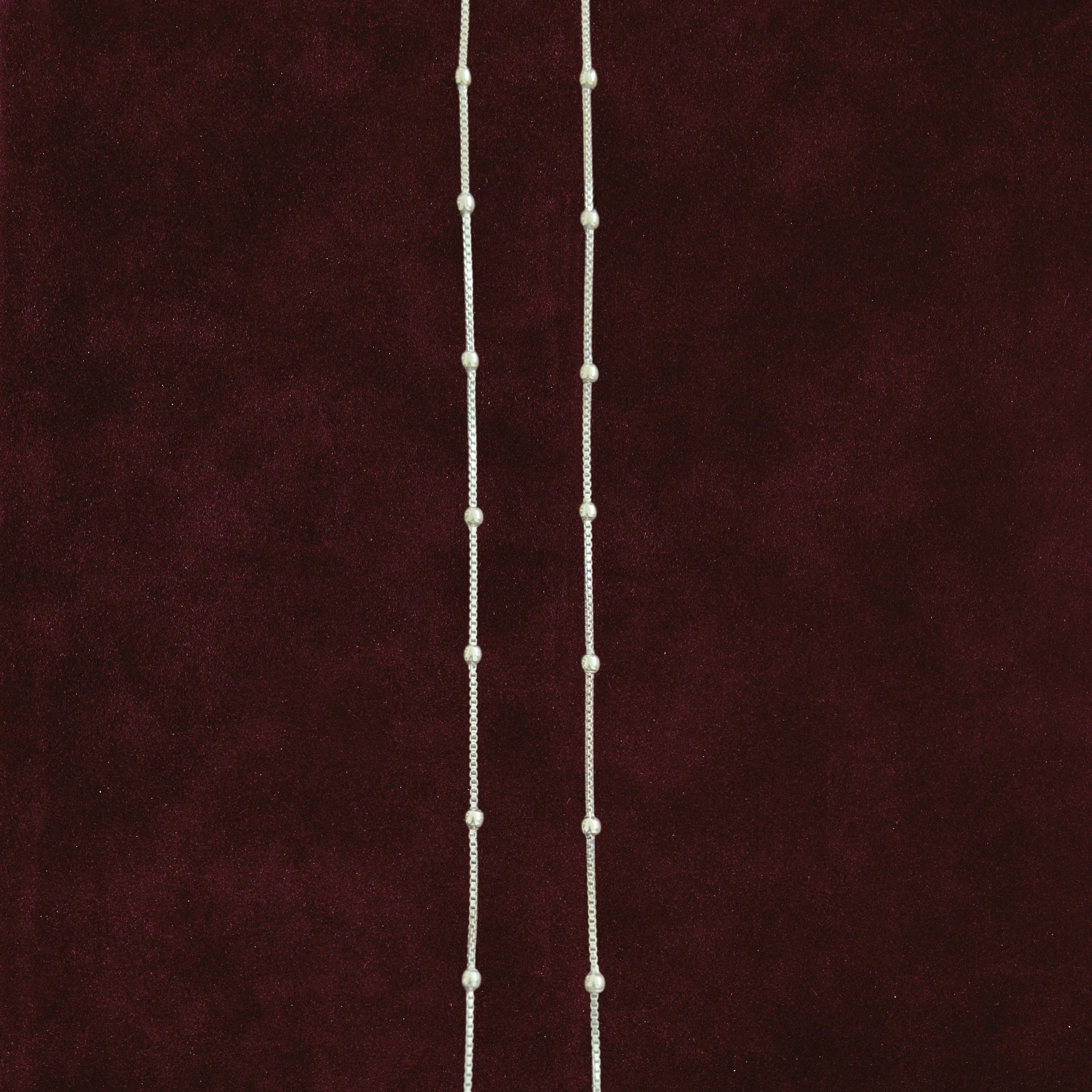 Silver dew drop anklet pair on maroon background