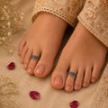 Feet with toe rings on a beige fabric background with flowers and petals.