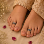 Feet with toe rings on a beige fabric background with flowers and petals.