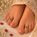 Close-up of feet with toe rings and floral decorations on a soft fabric background