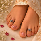 Close-up of feet with toe rings and floral decorations on a soft fabric background