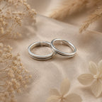 Two silver toe earrings on a beige fabric background with dried flowers.