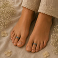 Feet with toe rings on a beige fabric background with flowers