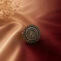 Victoria ring with intricate design on a textured fabric background