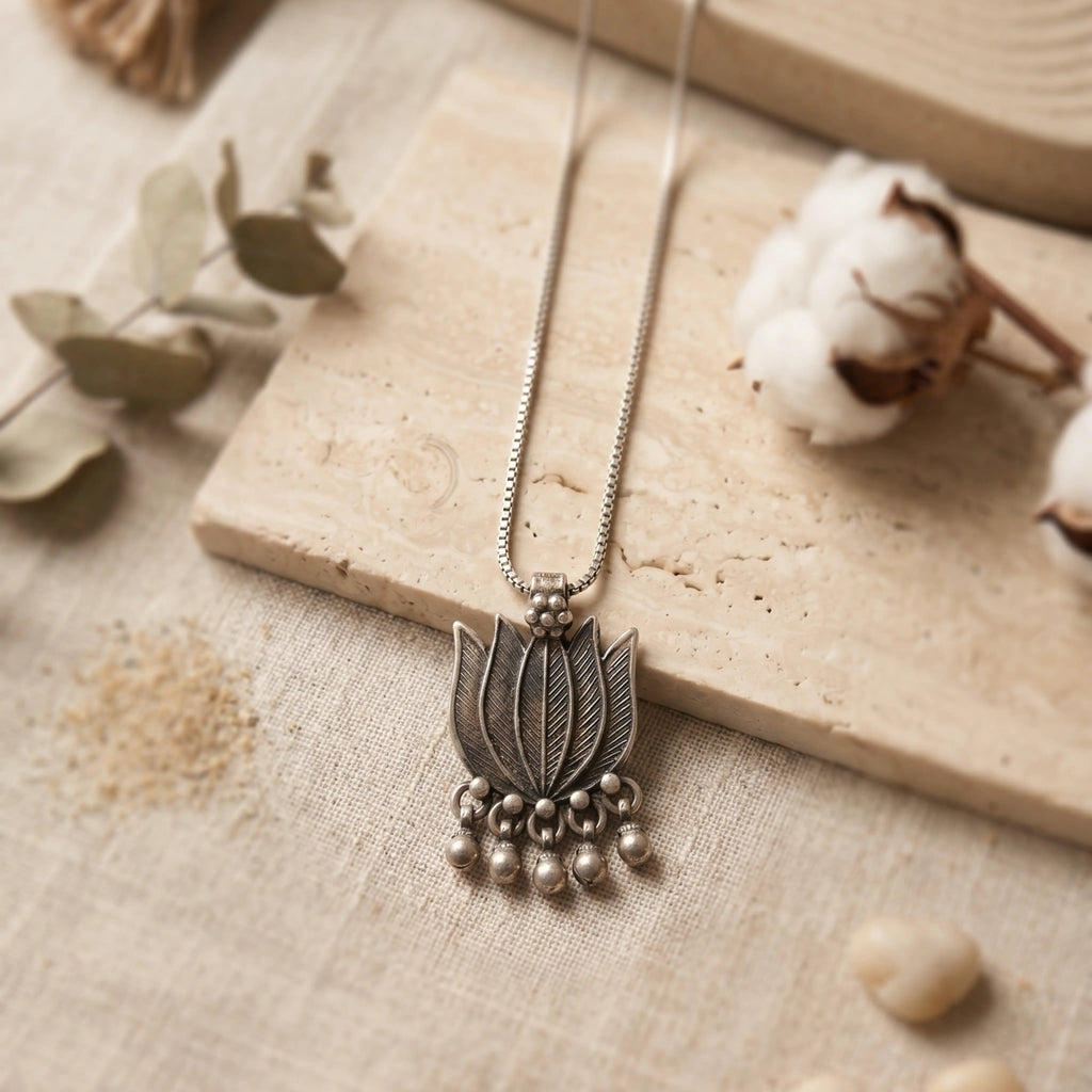 Silver necklace with a lotus pendant on a textured surface