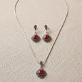 Jewelry set with necklace and earrings featuring red gemstones on a beige fabric background