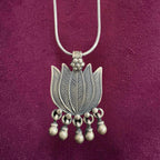 Silver necklace with a lotus-shaped pendant on a maroon background