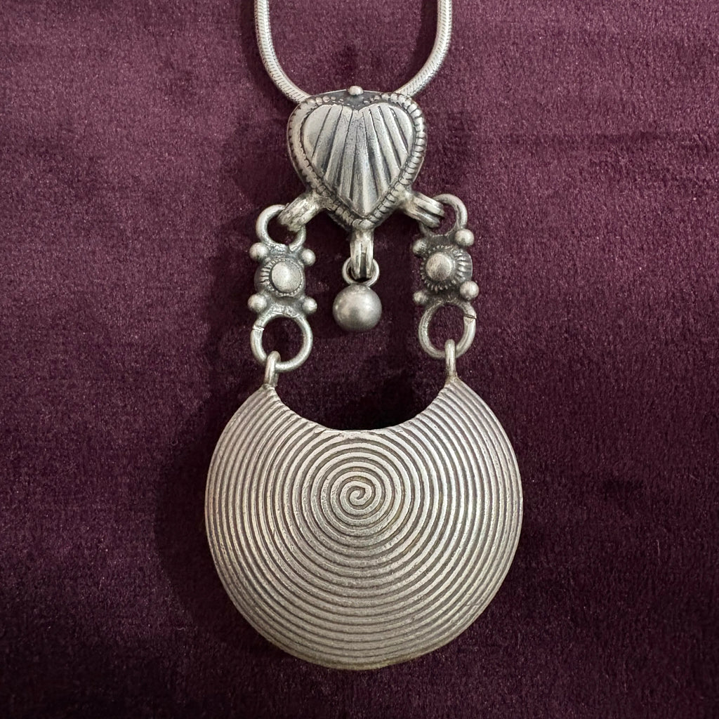 Silver pendant necklace on a maroon background