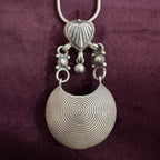 Silver pendant necklace on a maroon background