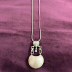 Silver necklace with a pendant on a maroon fabric background