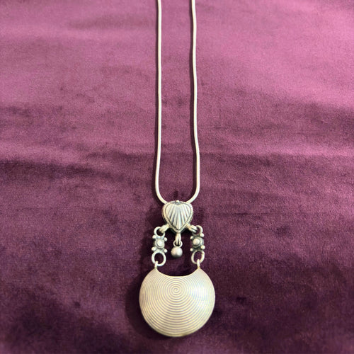 Silver necklace with a pendant on a maroon fabric background