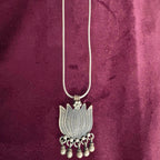 Silver necklace with a lotus-shaped pendant on a maroon fabric background