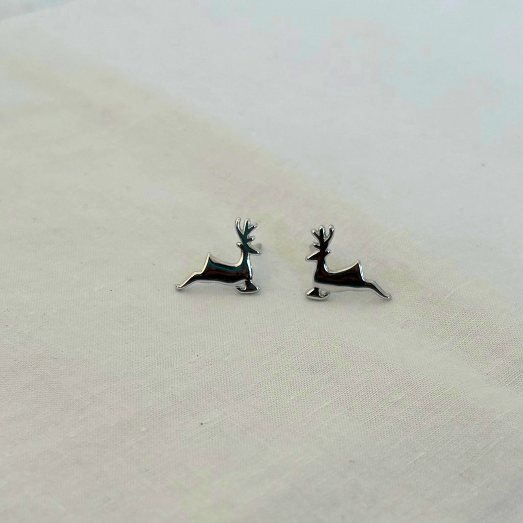 Deer-shaped earrings on a light fabric background