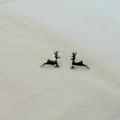 Deer-shaped earrings on a light fabric background
