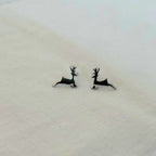 Deer-shaped earrings on a light fabric background