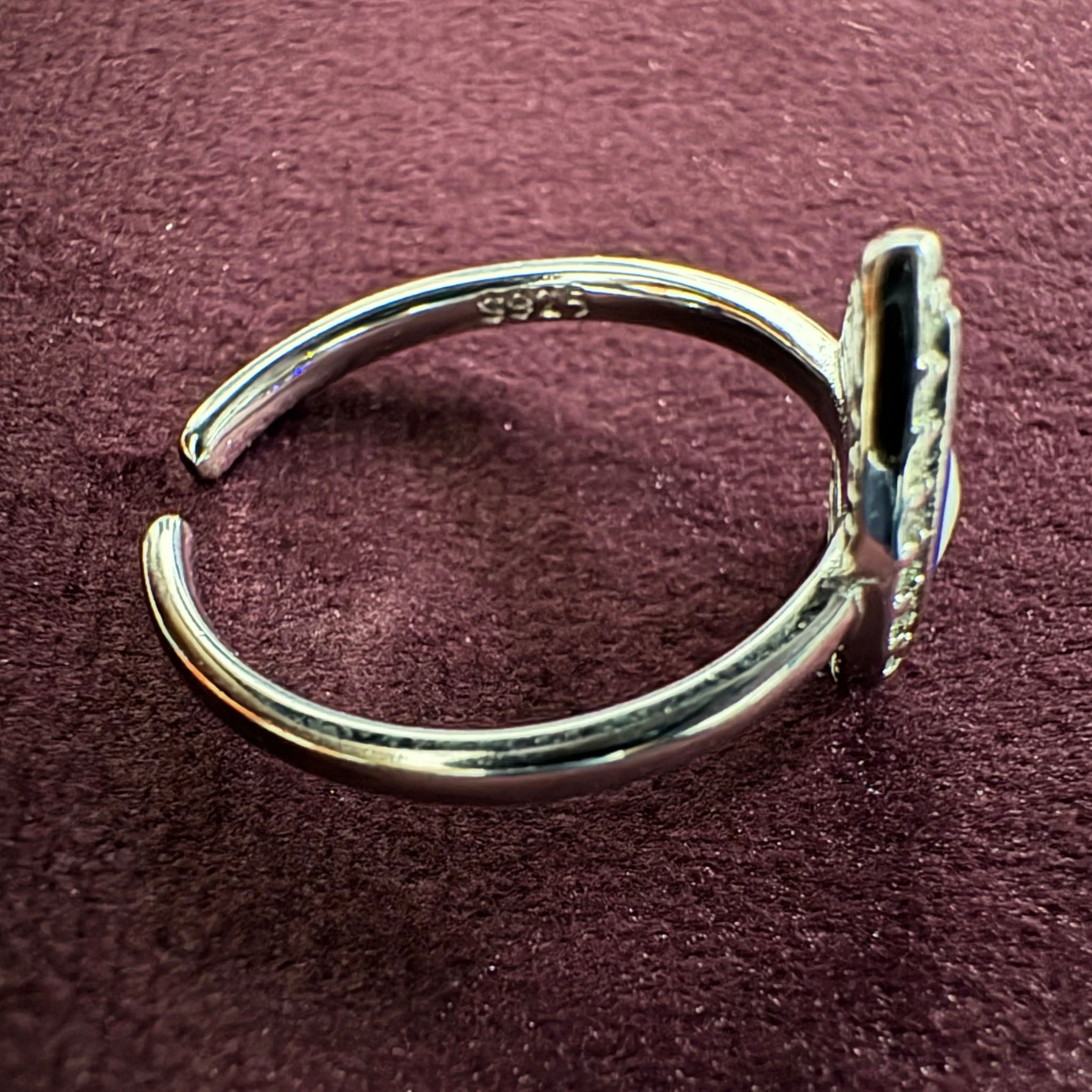 Silver toe ring with '925' stamp on a maroon surface