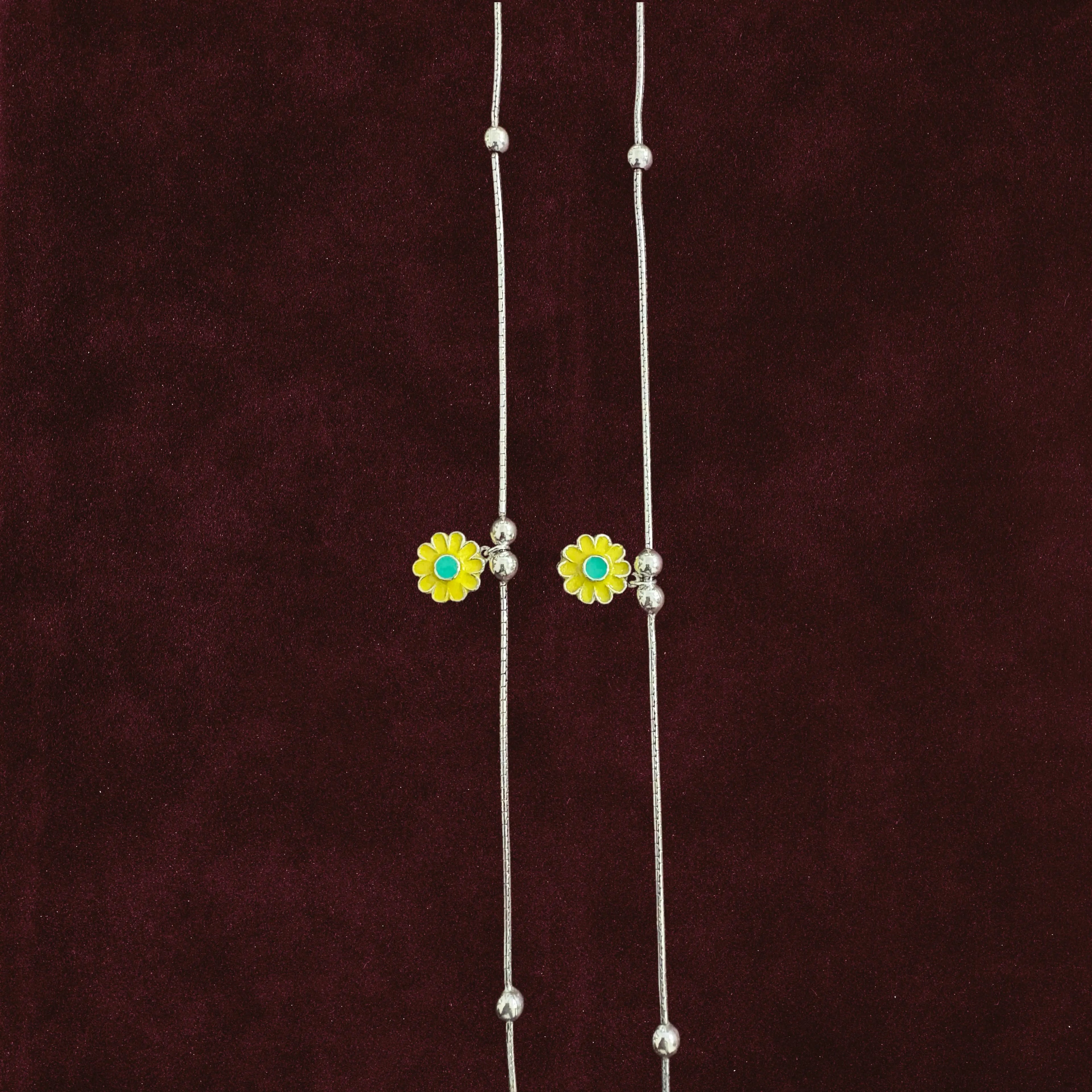 Close up of Sunflower Snake Chain Anklet Pair on maroon background