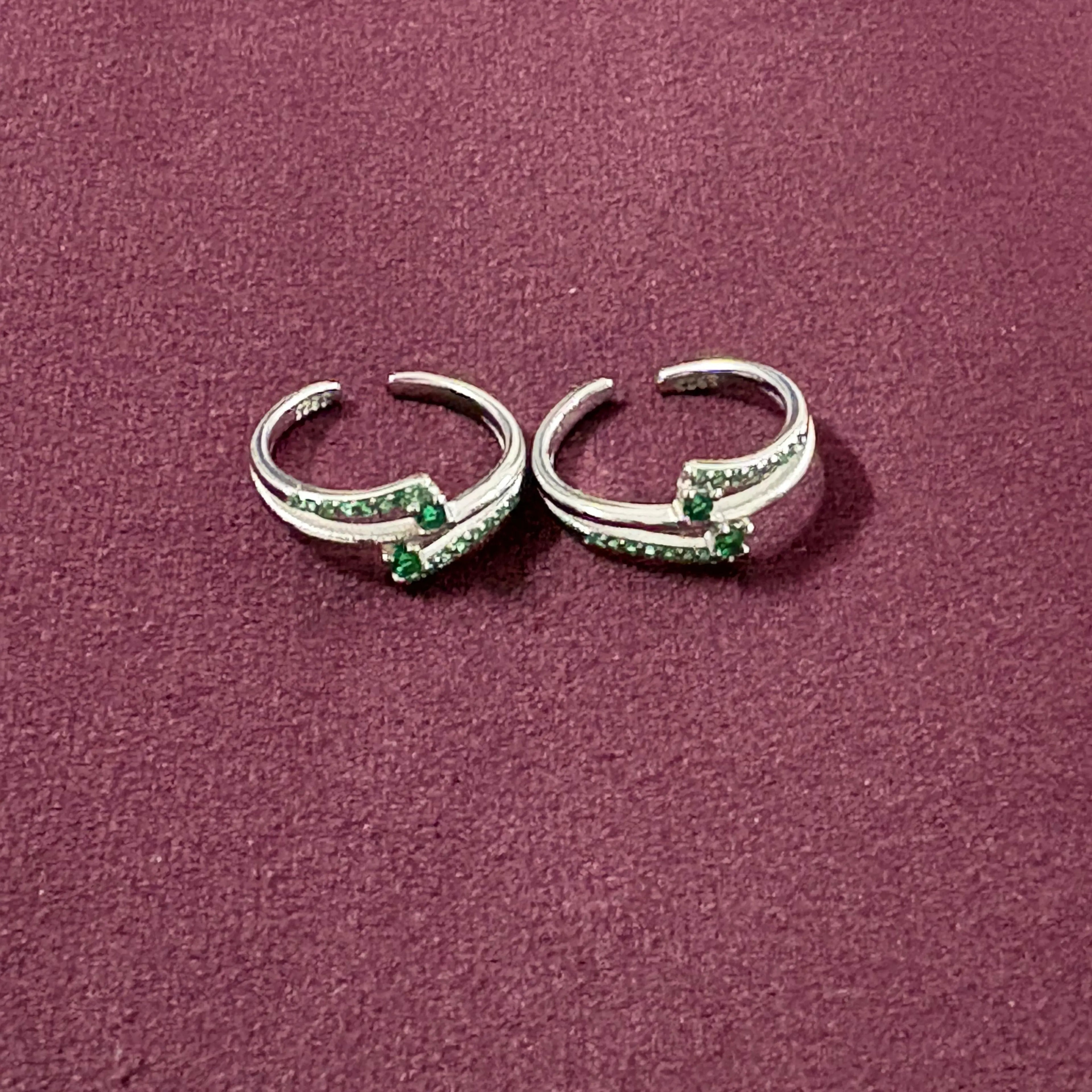Dual Arch Emerald Toe Rings on maroon background