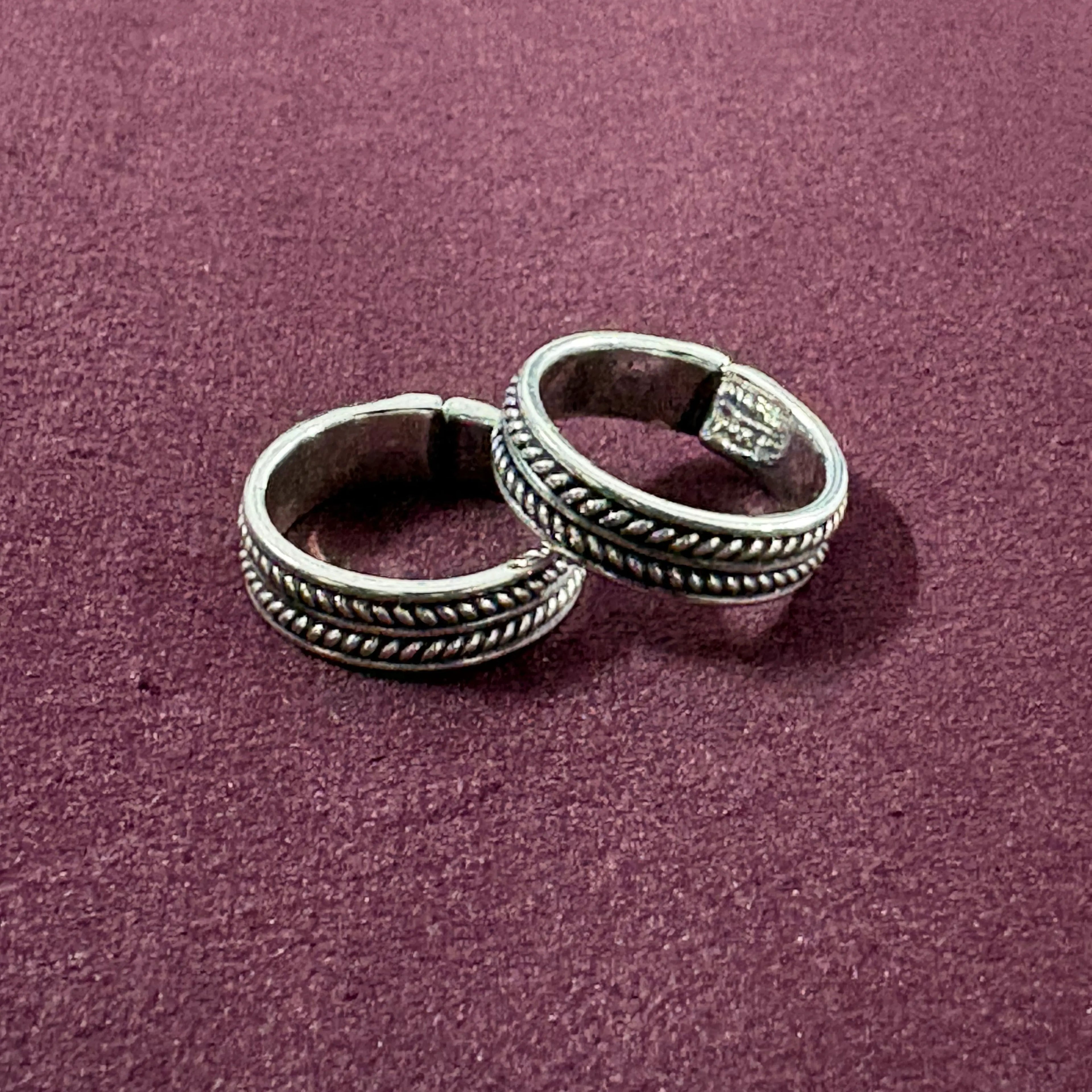 Flat lay image of Classic Rope Band Toe Rings on maroon background