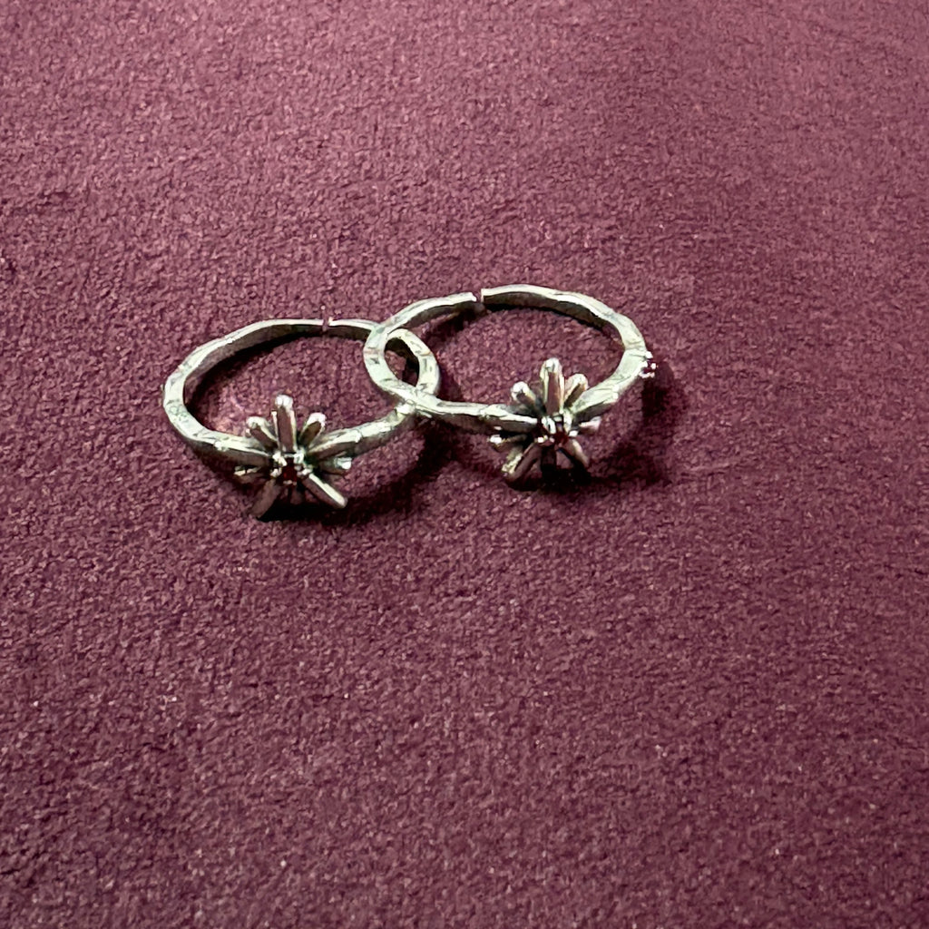Flat lay image of Starry Flora Oxidised Toe Rings on maroon background