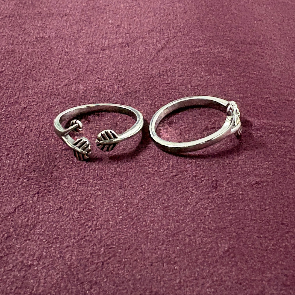 Flat lay image of Triple Leaf Open-Front Toe Rings on maroon background