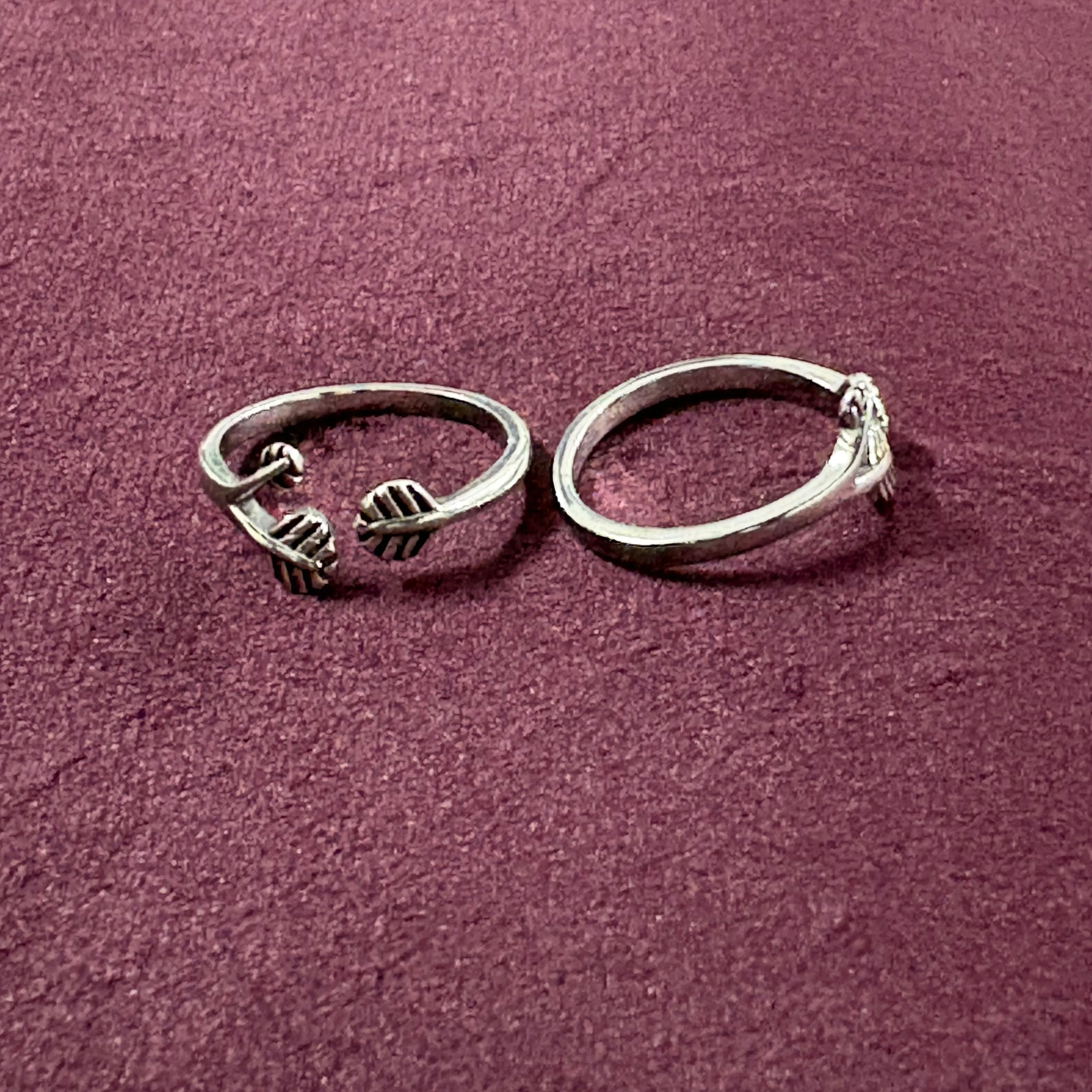 Flat lay image of Triple Leaf Open-Front Toe Rings on maroon background