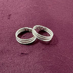 Flat lay image of Triple-Tier Rope Textured Band Toe Rings on maroon background
