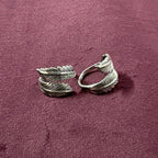 Flat lay image of Double Feather Oxidized Bypass Toe Rings on maroon background