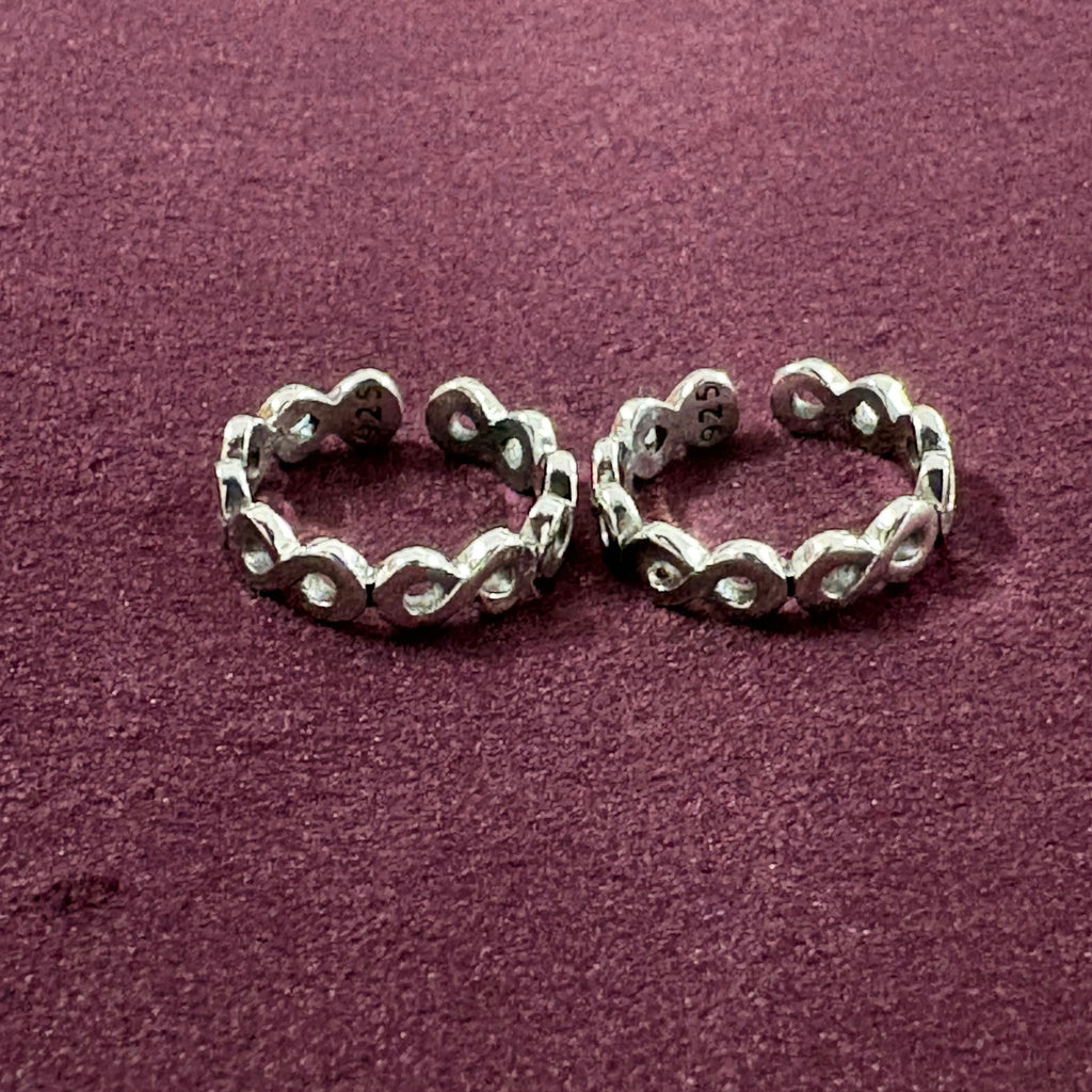 Flat lay image of Infinity Link Oxidized Toe Rings on maroon background