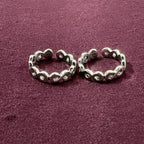 Flat lay image of Infinity Link Oxidized Toe Rings on maroon background