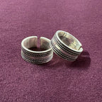 Flat lay image of Braided Oxidized Band Toe Rings on maroon background