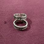 Flat lay image of Ivy Leaf toe ring pair on maroon background