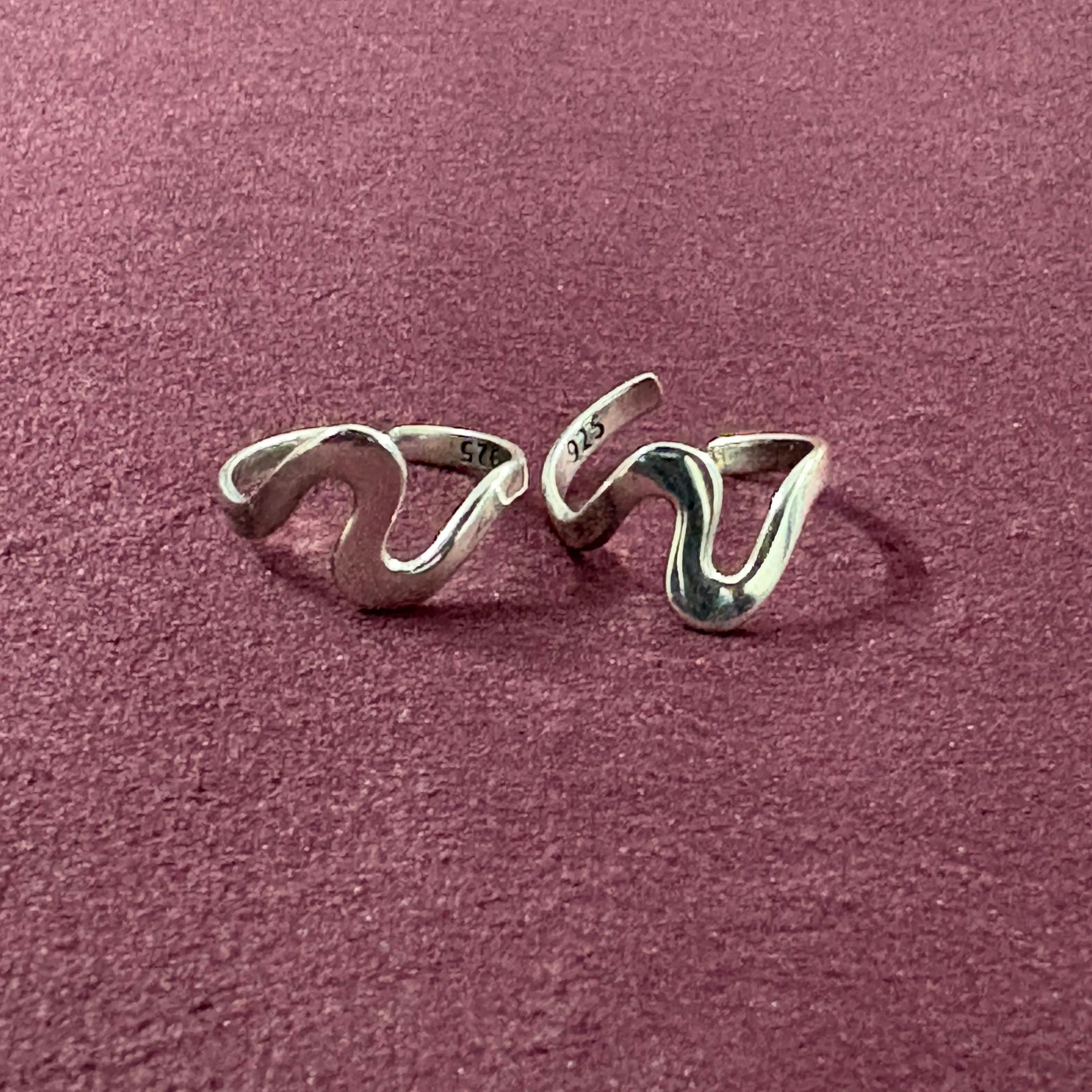Ebb & flow toe ring pair on maroon backgroun