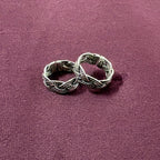 Flat lay image of Braided Filigree Oxidized Band Toe Rings on maroon background