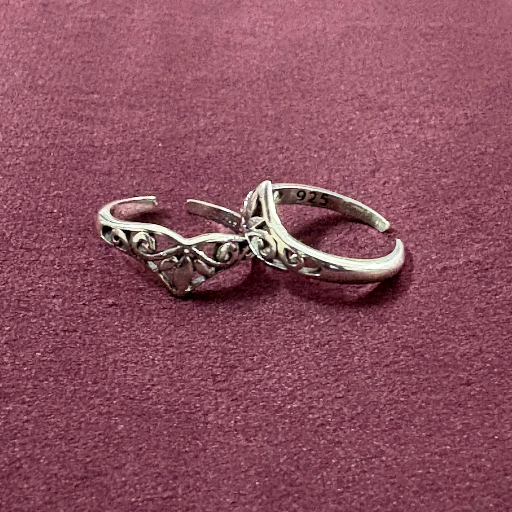Flat lay image of V-Shape Filigree Tiara Toe Rings on maroon background