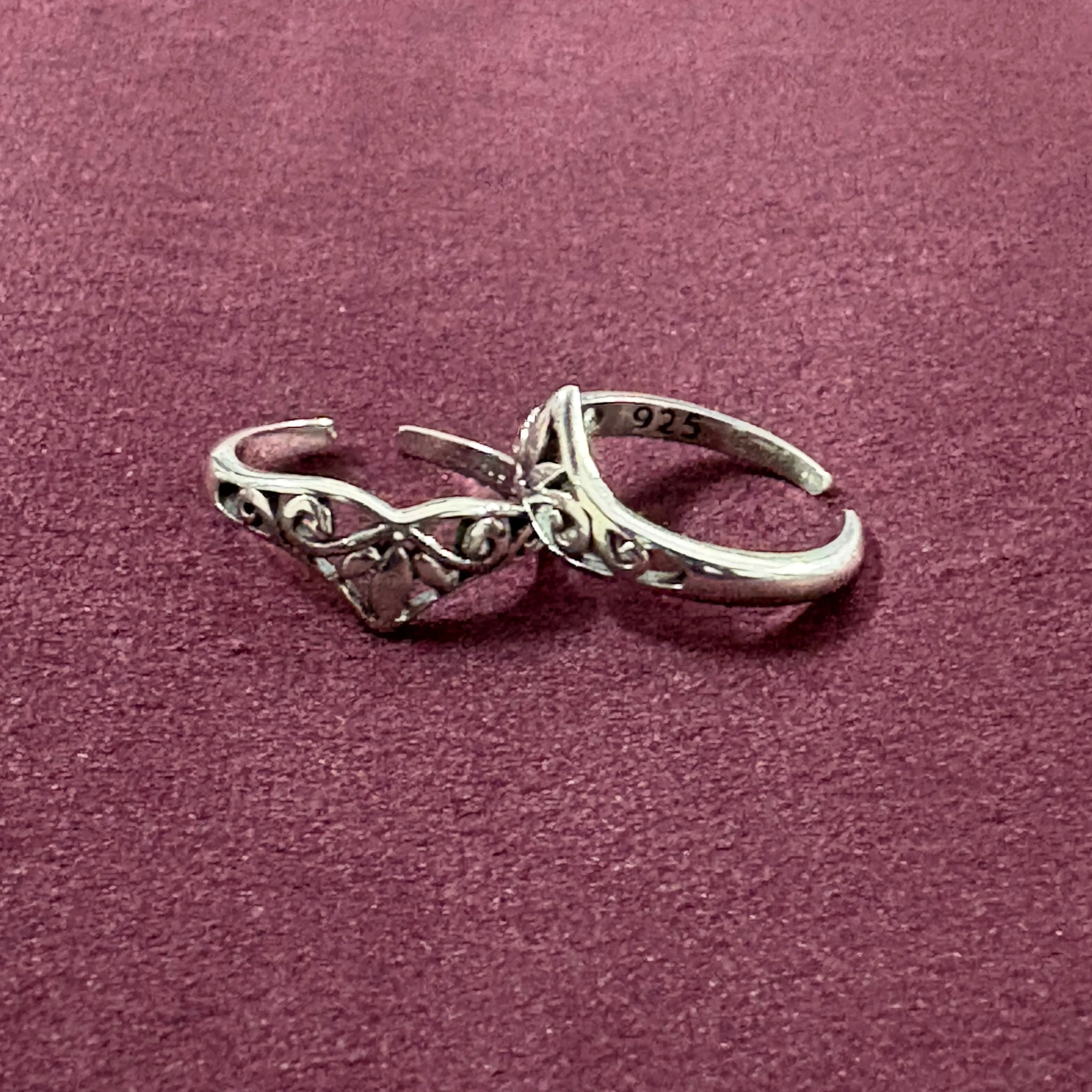 Flat lay image of V-Shape Filigree Tiara Toe Rings on maroon background