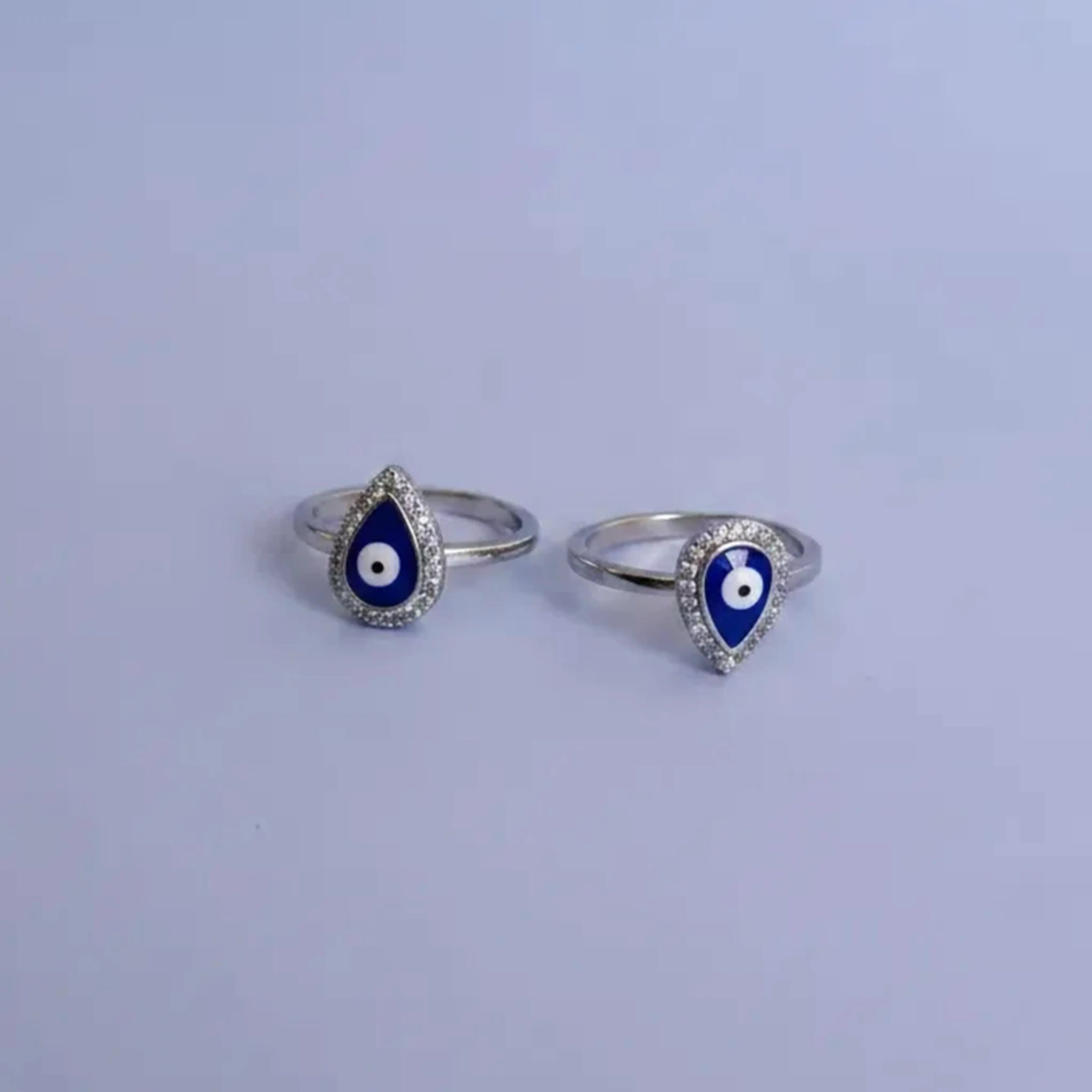Silver toe rings with blue and white evil eye design on a solid background
